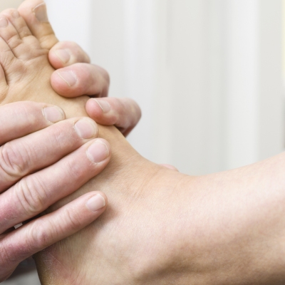 Ein Orthopädieschuhtechniker untersucht beide Füße im Detail.